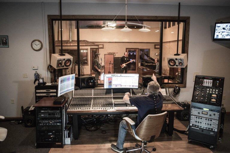 An engineer sat behind a large recording desk tracking a full band.